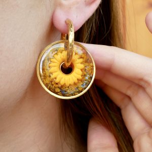pampilles interchangeables avec de véritables pétales de tournesol séchées et une fleur jaune en argile polymère portées à l'oreille